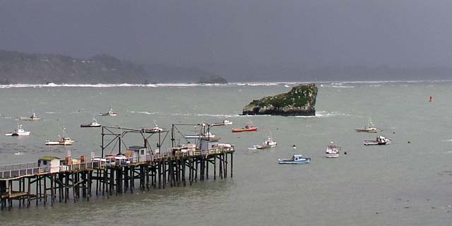 [Photo of pier, crab boats and Prisoner Rock]