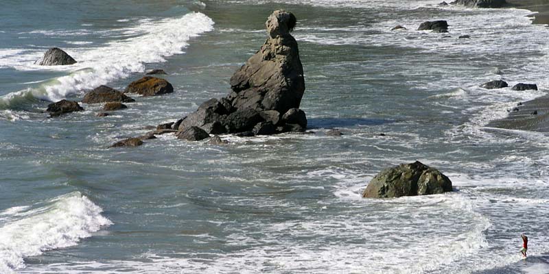 [Photo of rocks and girl playing in the surf]